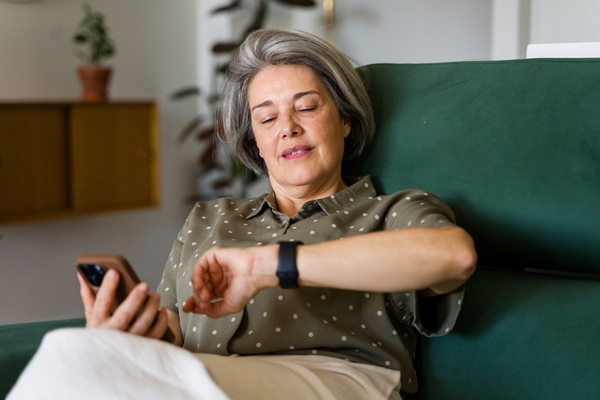  Kvinna som tittar på sin Apple Watch och sin telefon