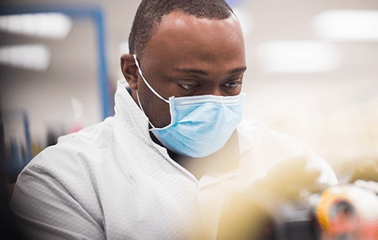 Man med mask som arbetar i laboratorium