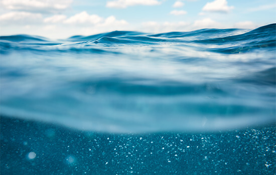 Foto på havsvågor med blå himmel, tagen från vattnet